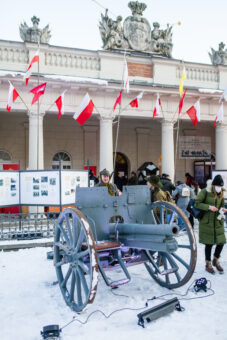 Grupa rekonstrukcji historycznej w mundurach, szytych na wzór tych z Powstania Wielkopolskiego. Stoją przed Odwachem przy zabytkowej armacie.